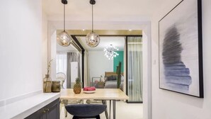 A modern kitchen with a dining area, featuring a wooden table, two pendant lights, and a large framed artwork on the wall. - Book and Bed - Lujiazui (Shanghai)