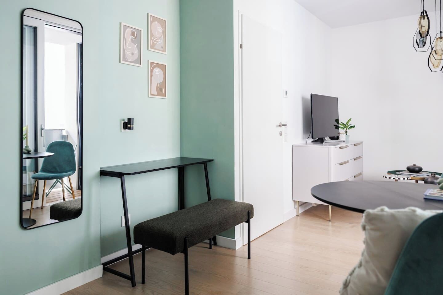 Ein modernes Wohnzimmer mit einer Bank, einem Tisch, einem Fernseher und einer Tür.