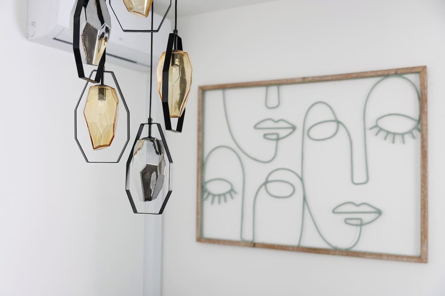 Una habitación con un cuadro abstracto geométrico en la pared y una lámpara moderna en el techo.
