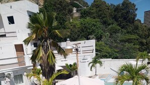 Un espace piscine aménagé sur le toit, avec des chaises longues, une piscine et un escalier menant à un niveau supérieur.