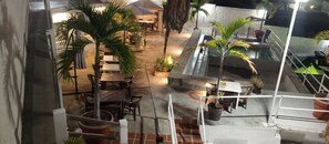 An outdoor patio area with tables and chairs, surrounded by potted plants and a small pool. - Hotel 10 minutes from the airport shuttle airport 24 hours breakfast included (Catia La Mar)