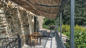 Un bâtiment en pierre doté d’un balcon, de mobilier d’extérieur et d’une pergola offrant de l’ombre.