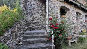 Un bâtiment en pierre à l’aspect rustique, avec un escalier en pierre menant à une porte.