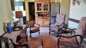 Un salon chaleureux avec des meubles en bois, un coin repas avec une table et des chaises, et une cuisine équipée de placards et d’un réfrigérateur.