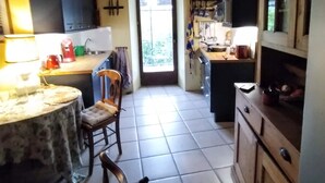 Une cuisine avec des meubles de rangement en bois, un sol carrelé et un coin repas comprenant une table et des chaises.