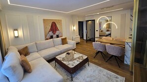 A modern living room with a sofa, coffee table, and dining area. - Apartments Lura (Peć)