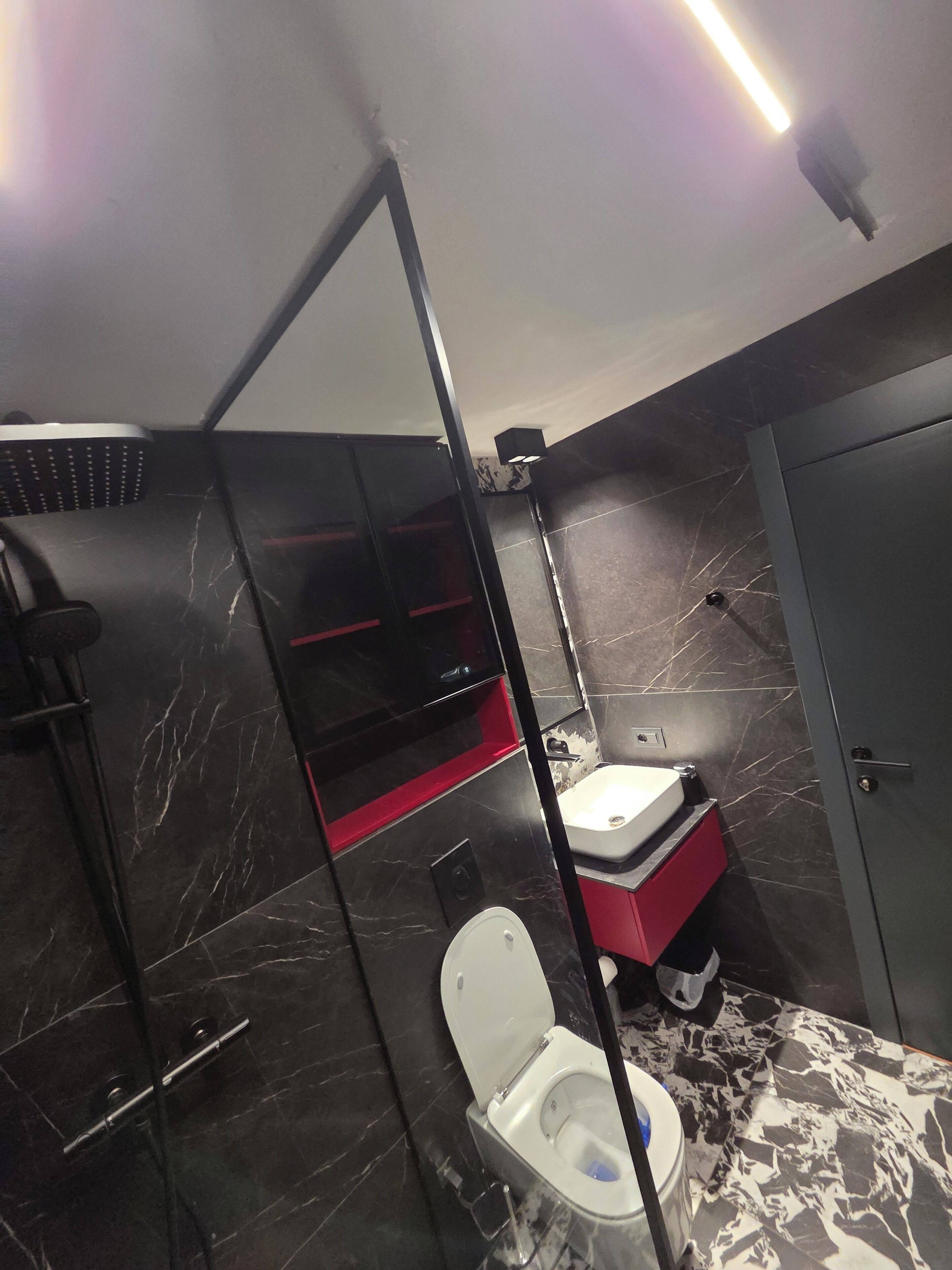 A compact bathroom with a toilet, a shower enclosure, and a sink.
