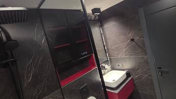 A compact bathroom with a toilet, a shower enclosure, and a sink.