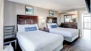 Une chambre d’hôtel avec deux lits, un bureau, une chaise, une commode et un téléviseur.