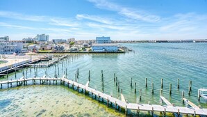A waterfront property with a dock extending into the water, a building with a blue roof, and a clear view of the surrounding area. - Thunder Island 161d 2 Bedroom Condo (Ocean City)
