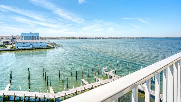 A waterfront property with a dock, a building with a blue roof, and a clear view of the water. - Thunder Island 161d 2 Bedroom Condo (Ocean City)