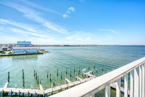 A waterfront property with a dock, a building with a blue roof, and a clear view of the water. - Thunder Island 161d 2 Bedroom Condo (Ocean City)