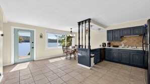 A kitchen with a view of a lake, a dining area with a table and chairs, and dark blue cabinets. - Lakefront Getaway With Private Dock & Scenic Views 3 Bedroom Home (Kingsport)