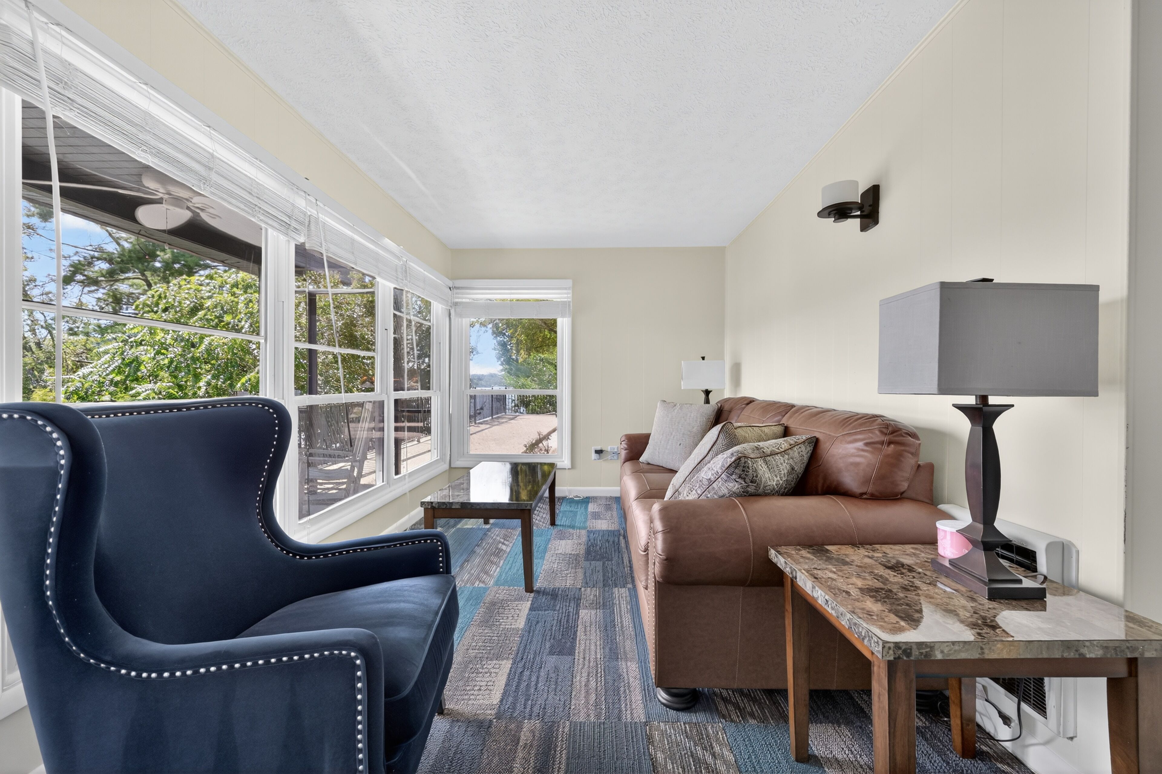 A modern living room with a leather sofa, a blue armchair, and a marble coffee table.