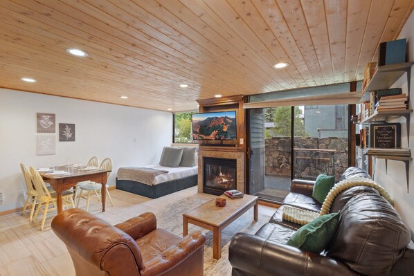 A cozy living room with a fireplace, leather sofas, a dining table with chairs, and a bookshelf. - Telluride Lodge 324 1 Bedroom Studio (Telluride)