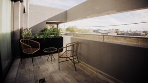 A balcony with two wicker chairs, a black planter with plants, and a view of the cityscape. - Edificio Coirón Premium (San Rafael)