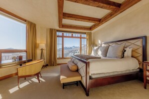 A bedroom with a large bed, a desk, a chair, and a window with a view of mountains. - One-Level See Forever by InvitedHome | Deck, Walk to Festivals, Developer’s Unit (Mountain Village)