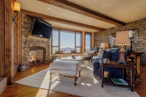 Una sala de estar acogedora con chimenea de piedra, ventanas amplias y vigas de madera.