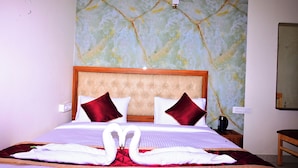 Une chambre d’hôtel avec un grand lit, un mur décoré d’un motif imitant le marbre et une tête de lit en bois.