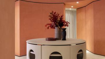 A circular seating area with a vase of red flowers on a table, surrounded by walls with a curved design.