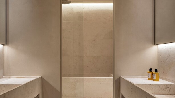 A modern bathroom with a central shower area, built-in shelves, and two sinks with toiletries. - Hotel Trame (Rome)