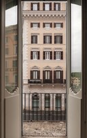 Un edificio con numerose finestre e balconi, visibile attraverso una porta in vetro.