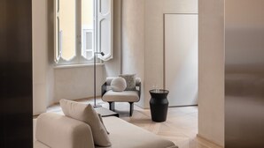 A minimalist living room with a sofa, a chair, a floor lamp, and a potted plant. - Hotel Trame (Rome)