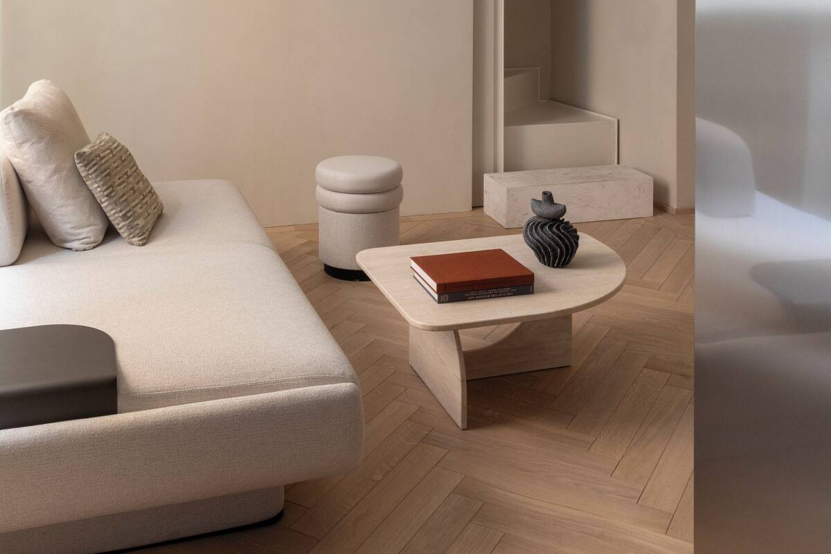 A modern living room with a sofa, a coffee table, and a staircase.