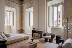 Una camera da letto moderna con un letto grande, una scrivania, una sedia e vista sulla città attraverso ampie finestre.