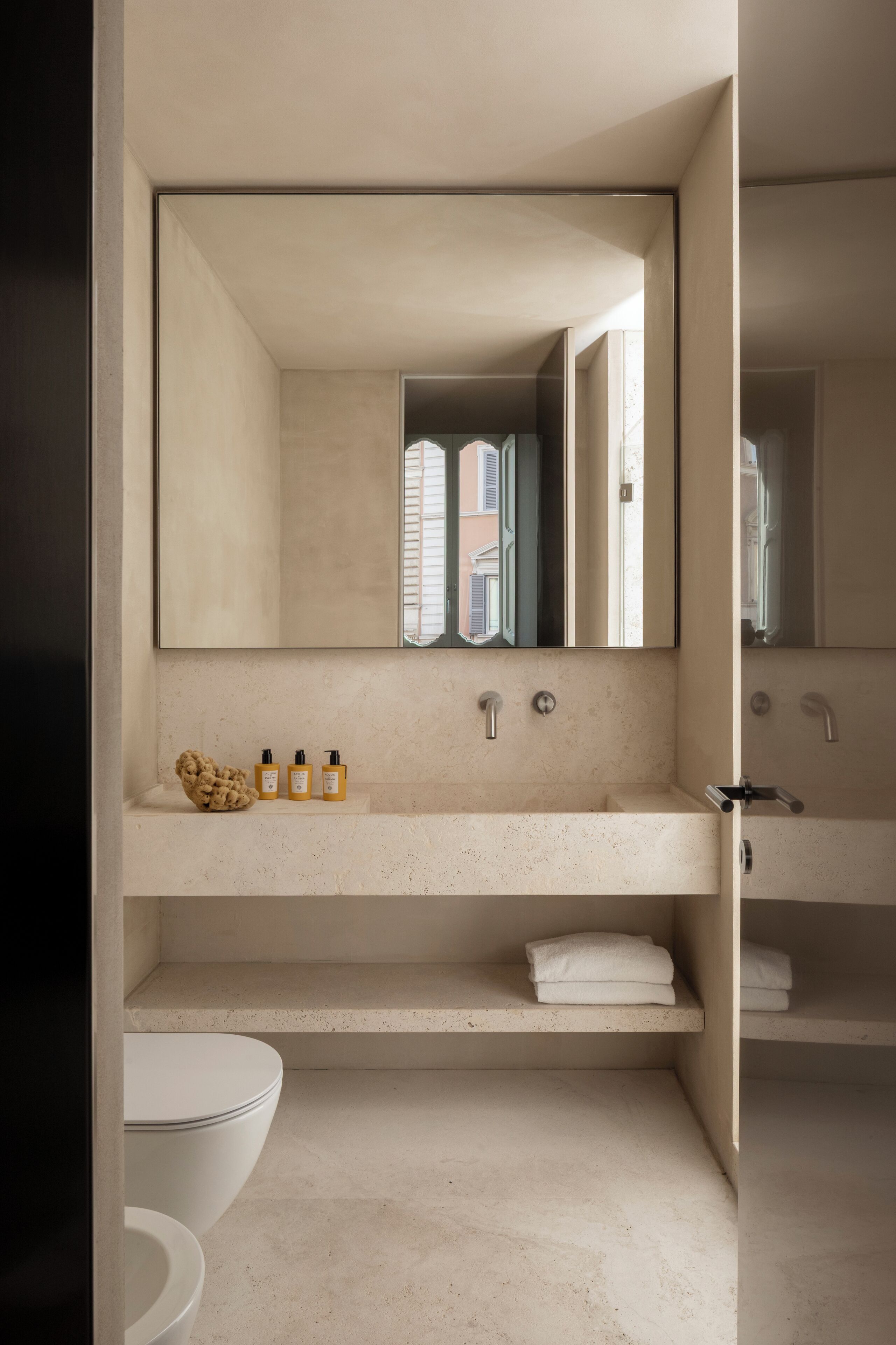 A modern bathroom with a large mirror, two sinks, and a toilet.
