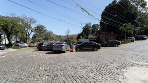 A cobblestone street with parked cars and buildings. - Loft em Condom nio com mar em Mangaratiba (Mangaratiba)