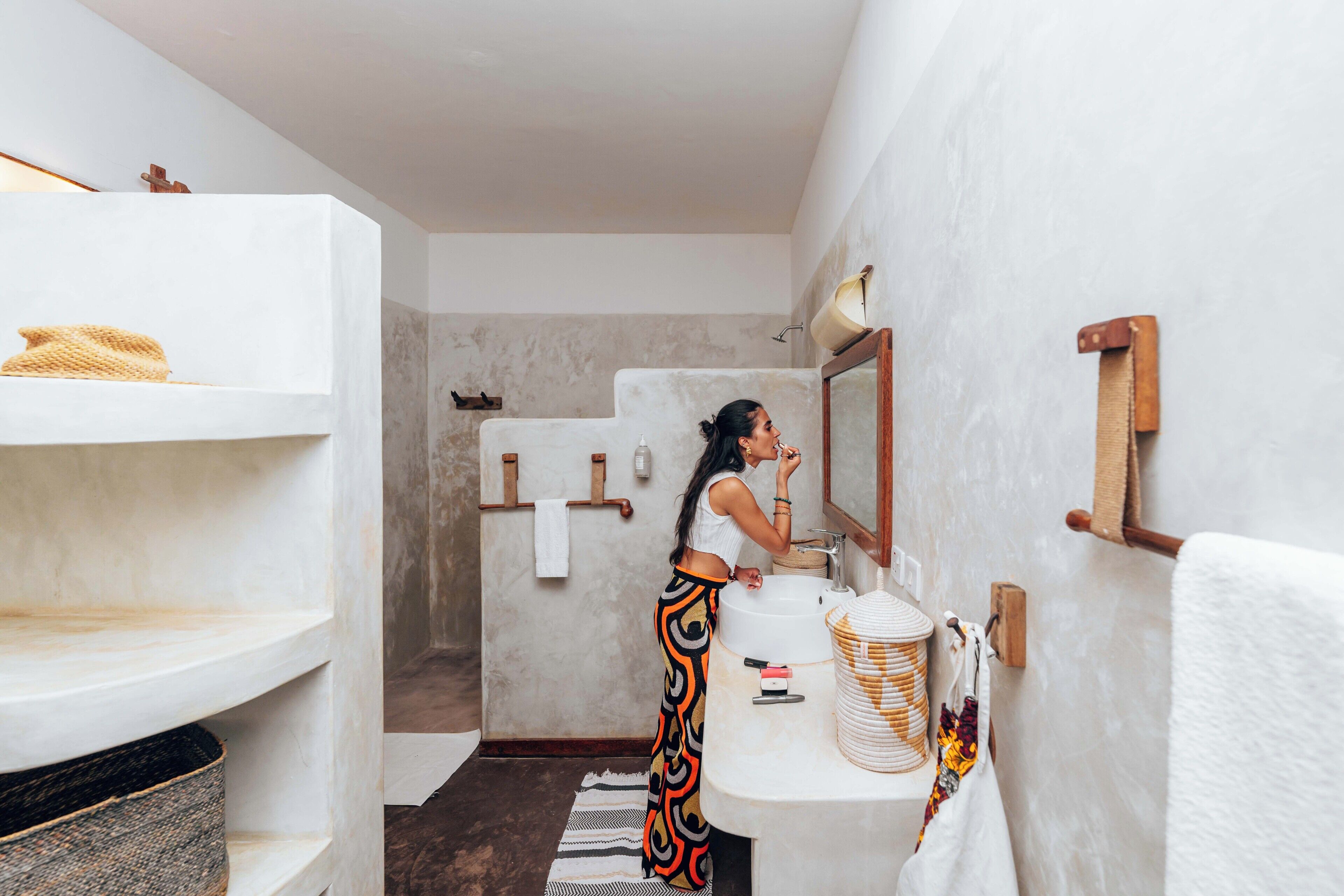 A modern bathroom with a white sink, mirror, and towel rack.