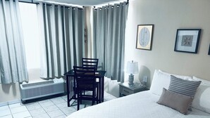 Une chambre d’hôtel avec un lit, une table et des chaises, un radiateur et des rideaux.