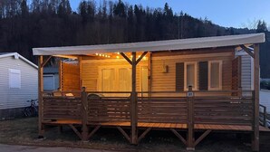 Een houten gebouw met een overdekte veranda, een fiets en een huisnummer '27'.