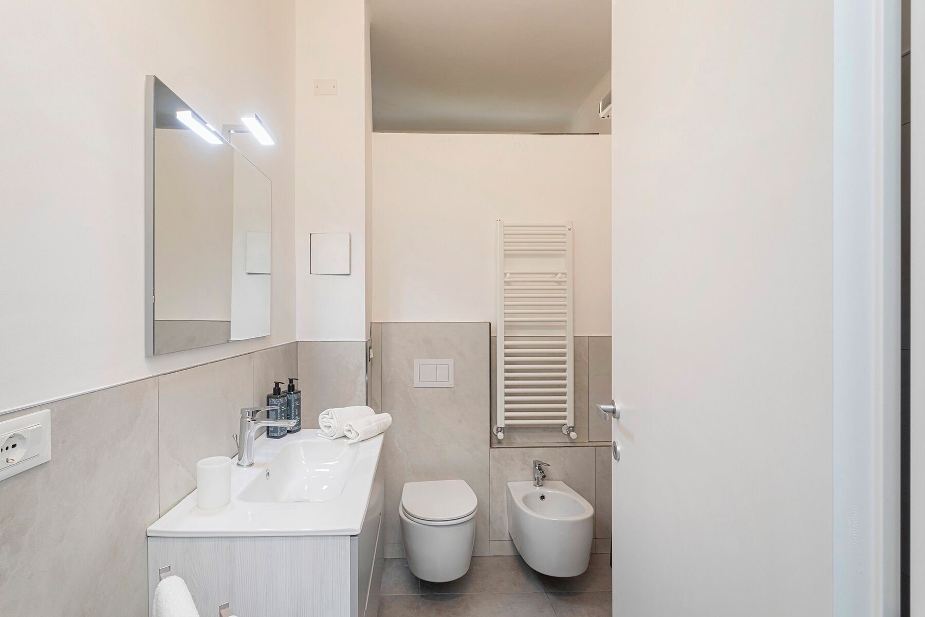 Une salle de bain moderne équipée d’un lavabo, de toilettes, d’un bidet et d’un porte-serviettes.