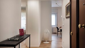 A hallway with a table, a fan, and a door leading to a dining area. - Quinto Modern Flat by Wonderful Italy (Genoa)