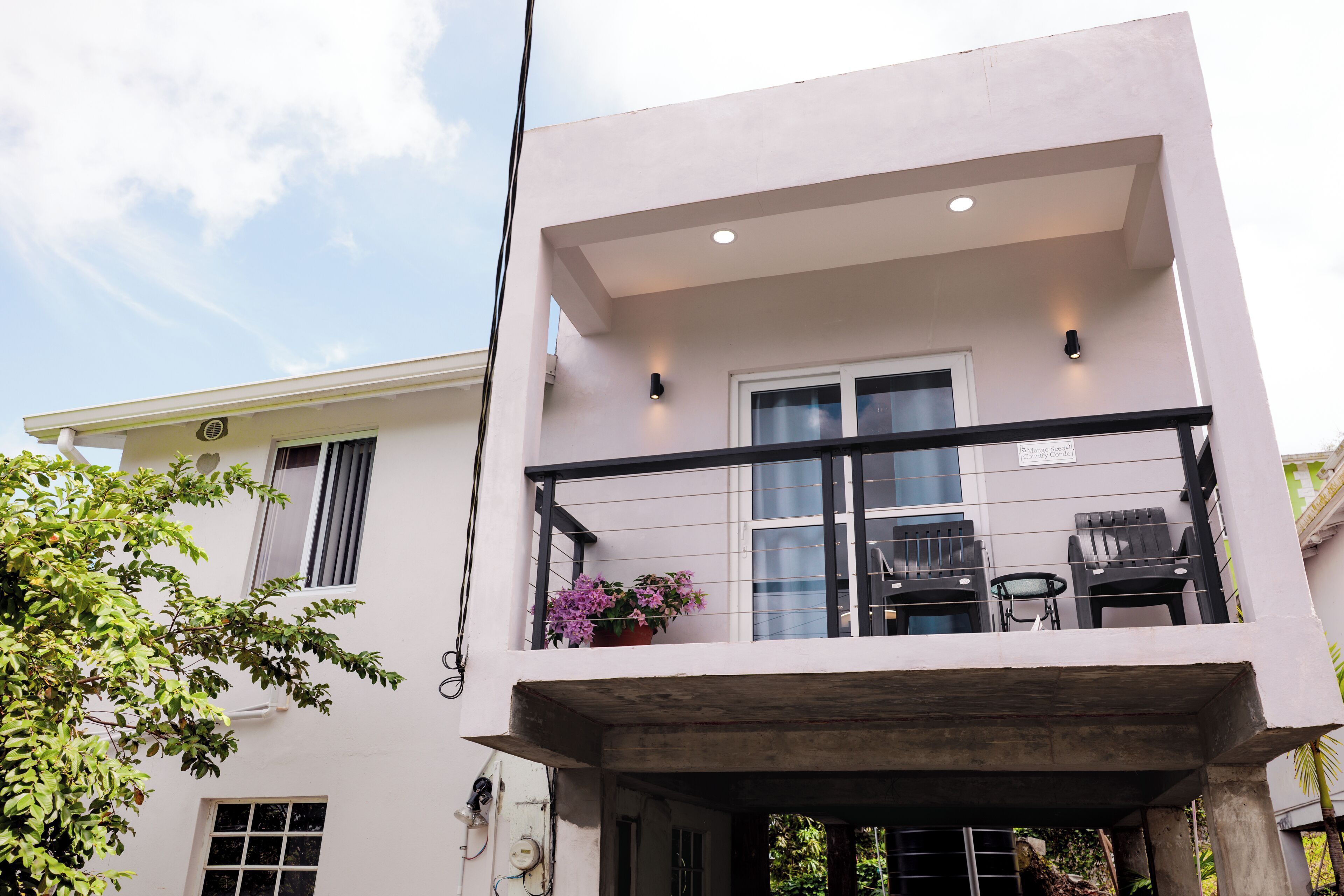 A modern two-story building with a balcony, a small table, and chairs.