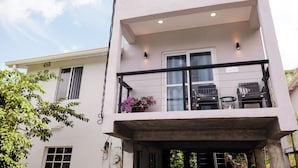 A modern two-story building with a balcony, a small table, and chairs. - Cozy 1-bedroom apartment in beautiful Grande Riviere with AC (Grande Riviere)