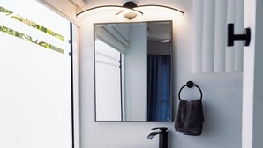 A modern bathroom with a large window, a white sink, a mirror, and a towel rack. - Cozy 1-bedroom apartment in beautiful Grande Riviere with AC (Grande Riviere)