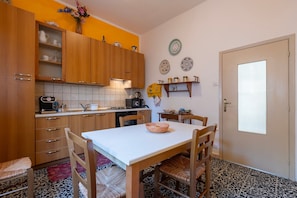 A kitchen with wooden cabinets, a white countertop, and a dining table with chairs.