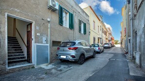 A narrow street with parked cars, a building with a staircase, and a clear sky. - Apartment 'Maria- Castelsardo' with Mountain View, Wi-Fi and Air Conditioning (Castelsardo)