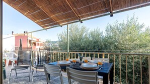 An outdoor dining area with a table set for four, surrounded by chairs, under a shaded pergola. - Apartment 'Maria- Castelsardo' with Mountain View, Wi-Fi and Air Conditioning (Castelsardo)