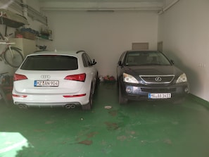 Two cars parked in a garage with green flooring and white walls. - Perpignan Appart 5 mns Centre, Palais Congrès et Exposition 5 people (5 Beds) (Perpignan)