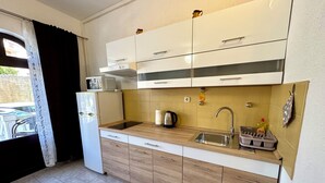 Una cucina compatta con lavello, fornello e microonde.