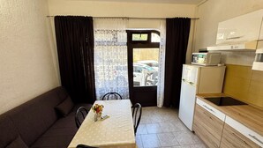 Un angolo cottura compatto con tavolo, sedie, divano e frigorifero.