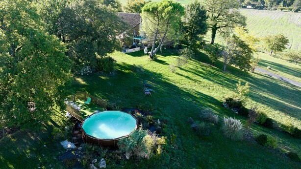 A house with a swimming pool surrounded by lush greenery and a hilly landscape. - Pech Chabrol: Family Cottage with Pool and Vineyard View (Ribagnac)
