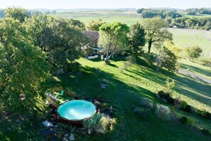 A house with a swimming pool surrounded by lush greenery and a hilly landscape. - Pech Chabrol: Family Cottage with Pool and Vineyard View (Ribagnac)