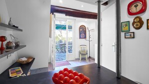 A kitchen with a fruit bowl, a wooden table, and a door leading to a patio. - Pech Chabrol: Family Cottage with Pool and Vineyard View (Ribagnac)