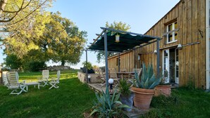 A wooden building with a covered patio area, outdoor seating, and potted plants. - Pech Chabrol: Family Cottage with Pool and Vineyard View (Ribagnac)