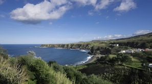 A coastal landscape with a view of the sea, cliffs, and a cluster of houses.